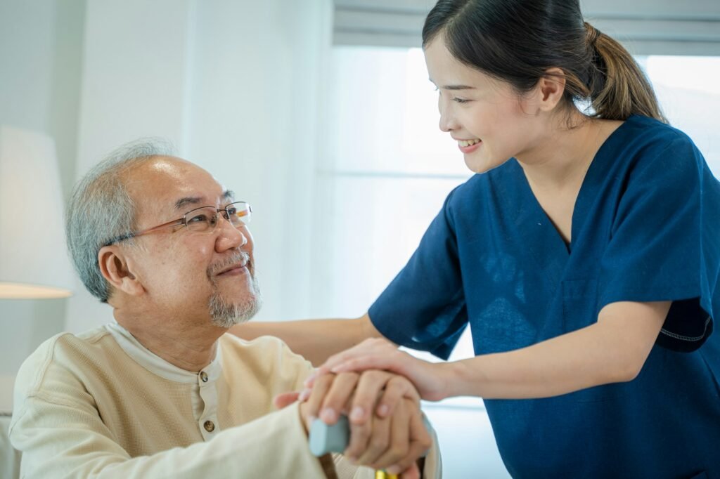 Caregiver talking to senior man in bedroom, Home care service.